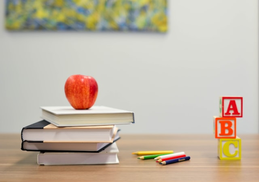 A red apple resting on a stack of books beside alphabet blocks